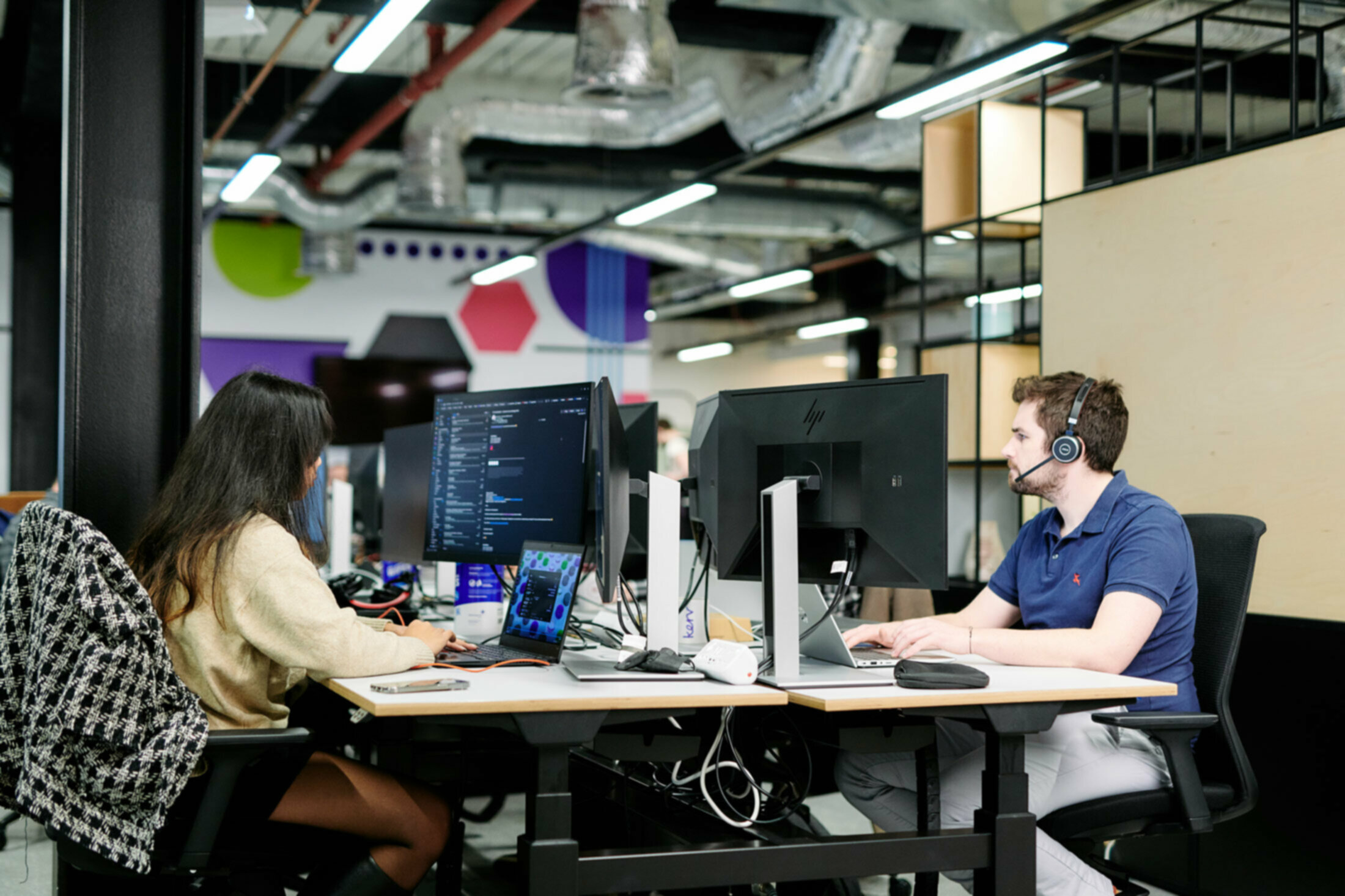 Two people sitting at computer desks in an office