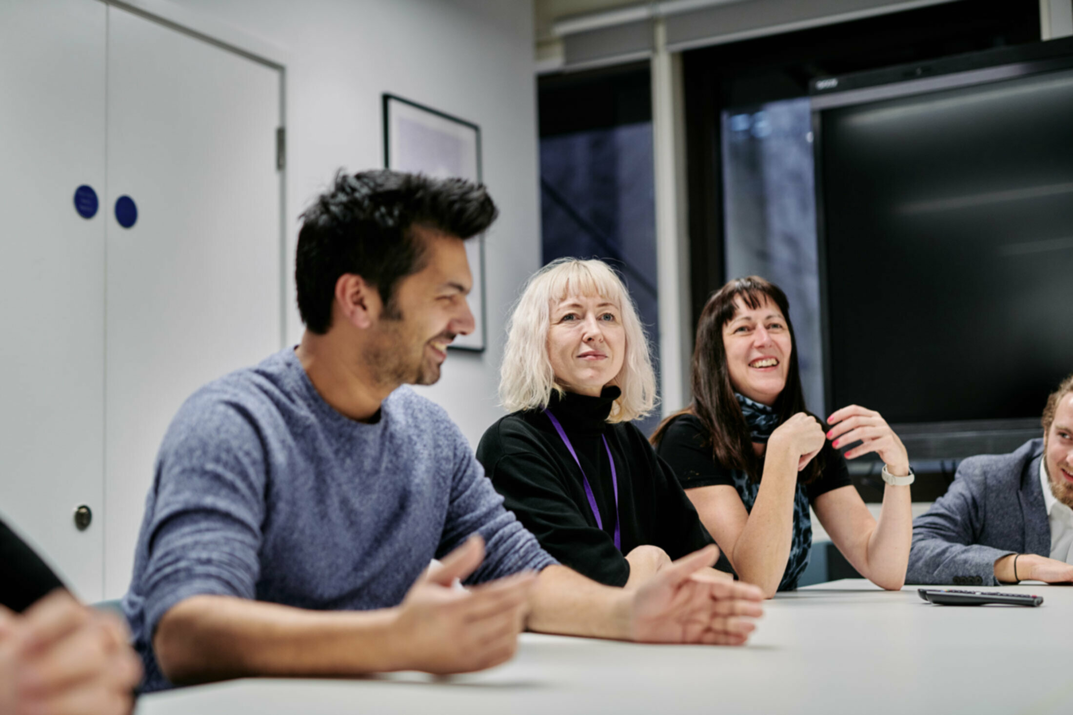 Three people sitting at office desk smiling