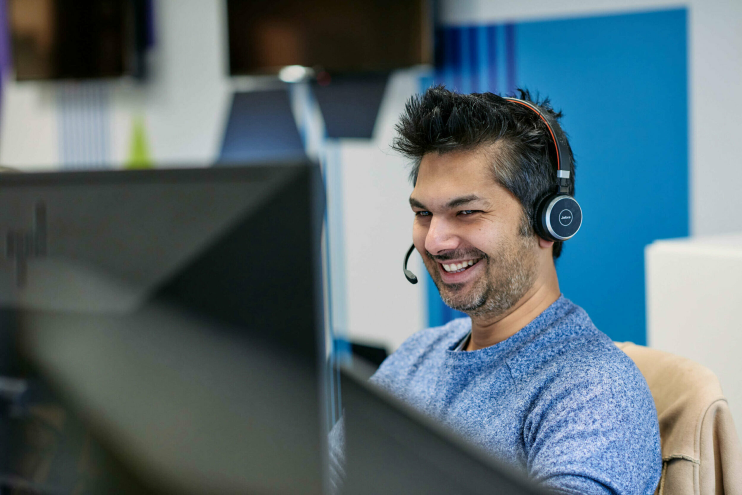 Man smiling at his computer wearing headphones.