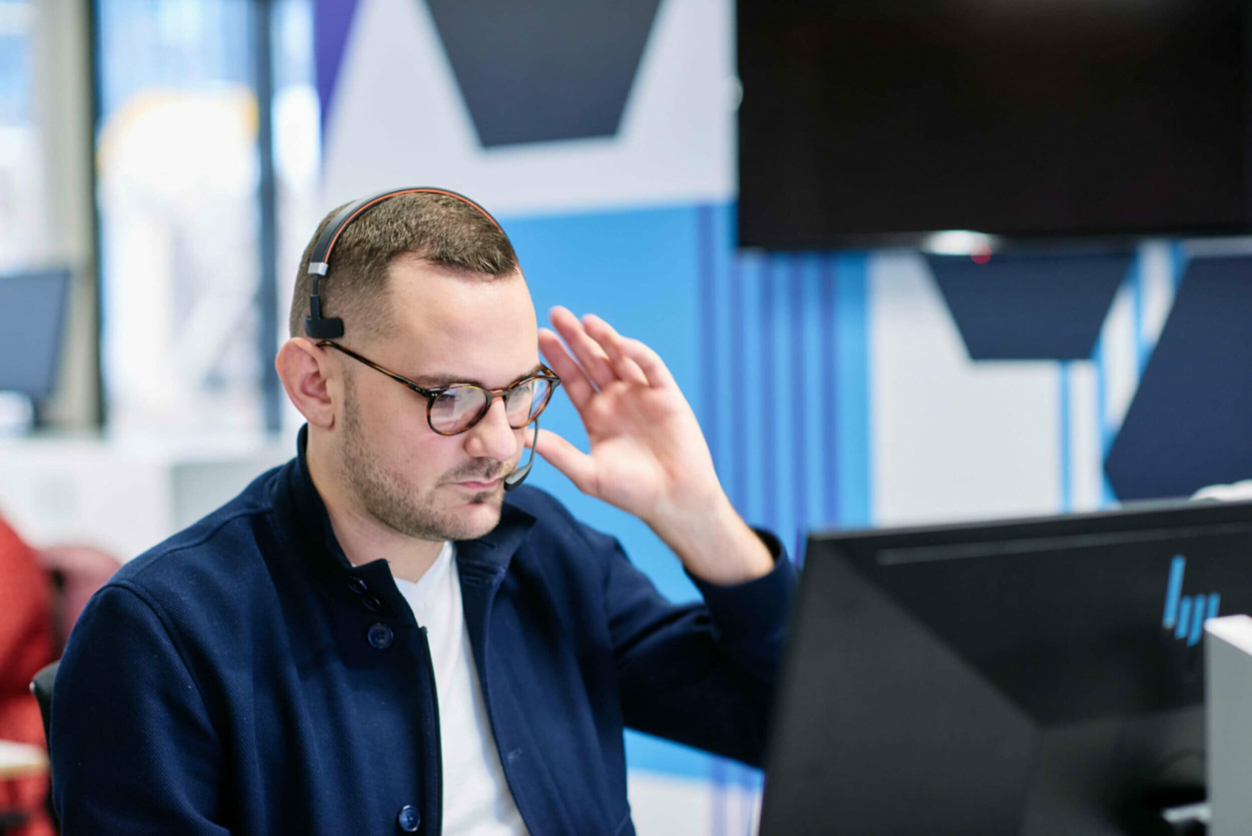 Man with headset sitting at computer desk in an office