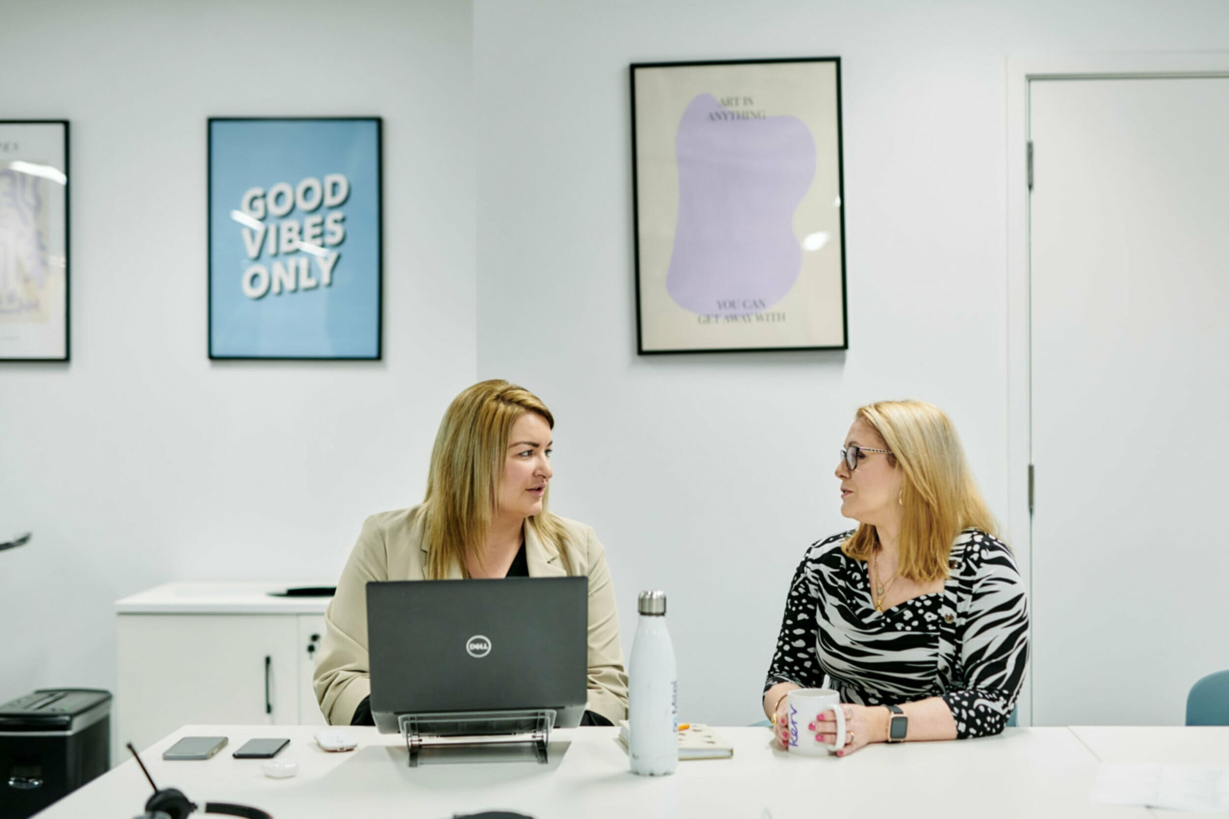 Two women sitting at office desk talking