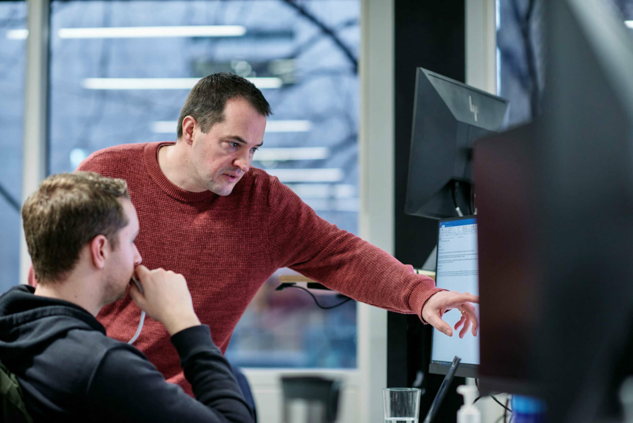 Two men in the office looking at computer at desk