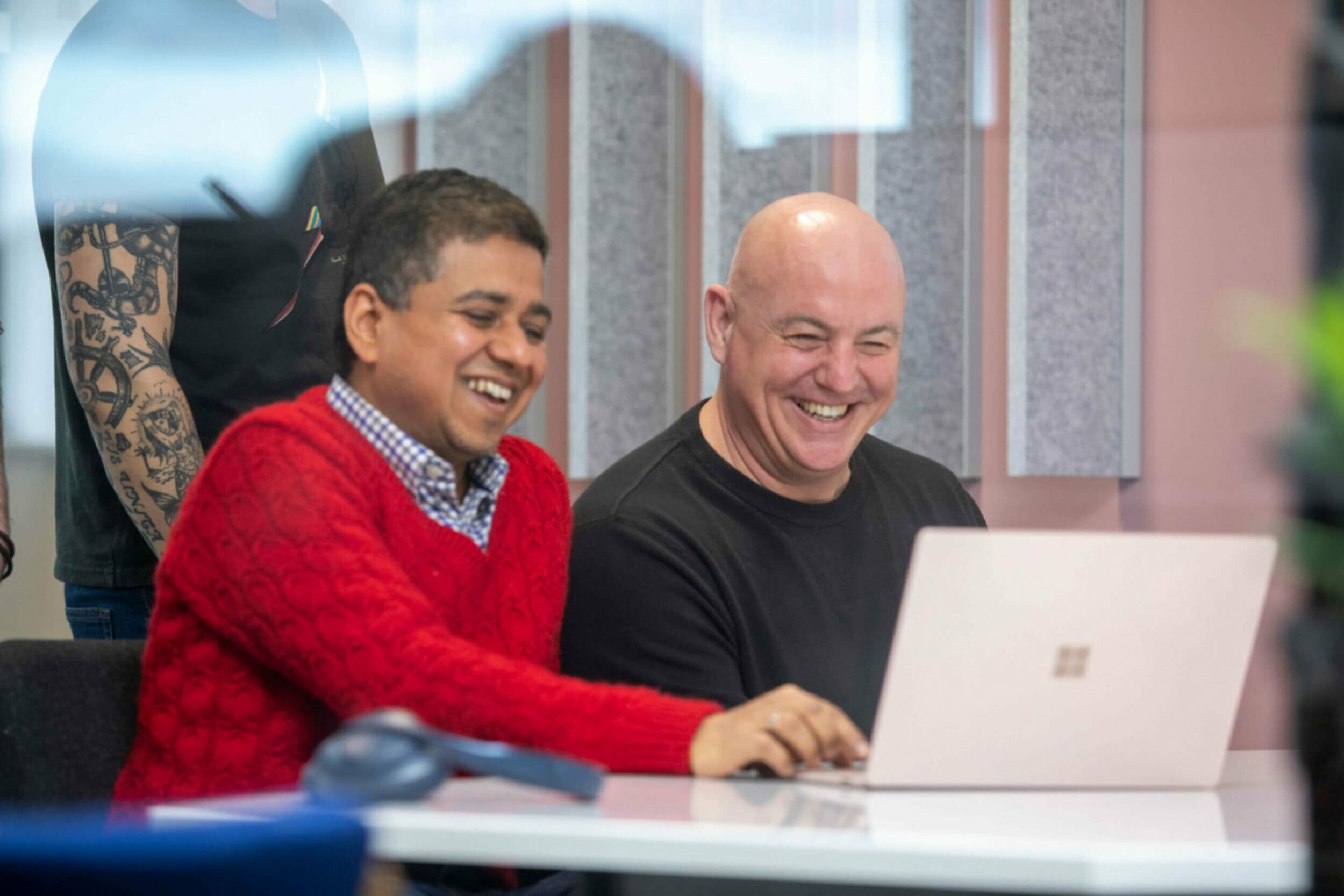 Two man sat at laptop smiling