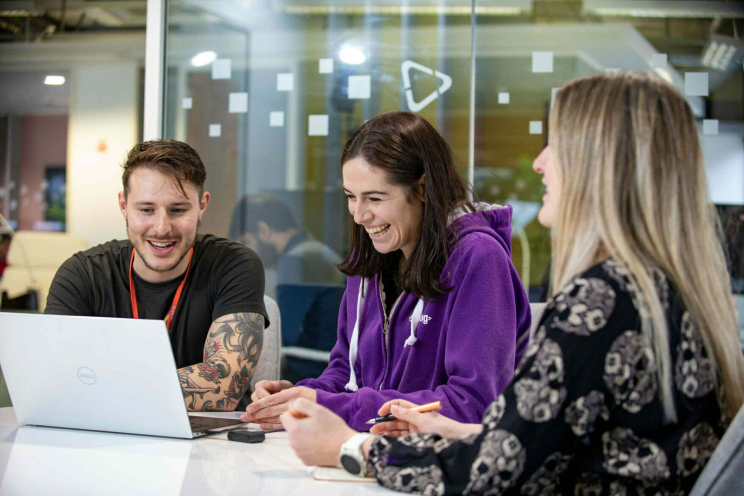 Two woman and a man around a laptop in an office