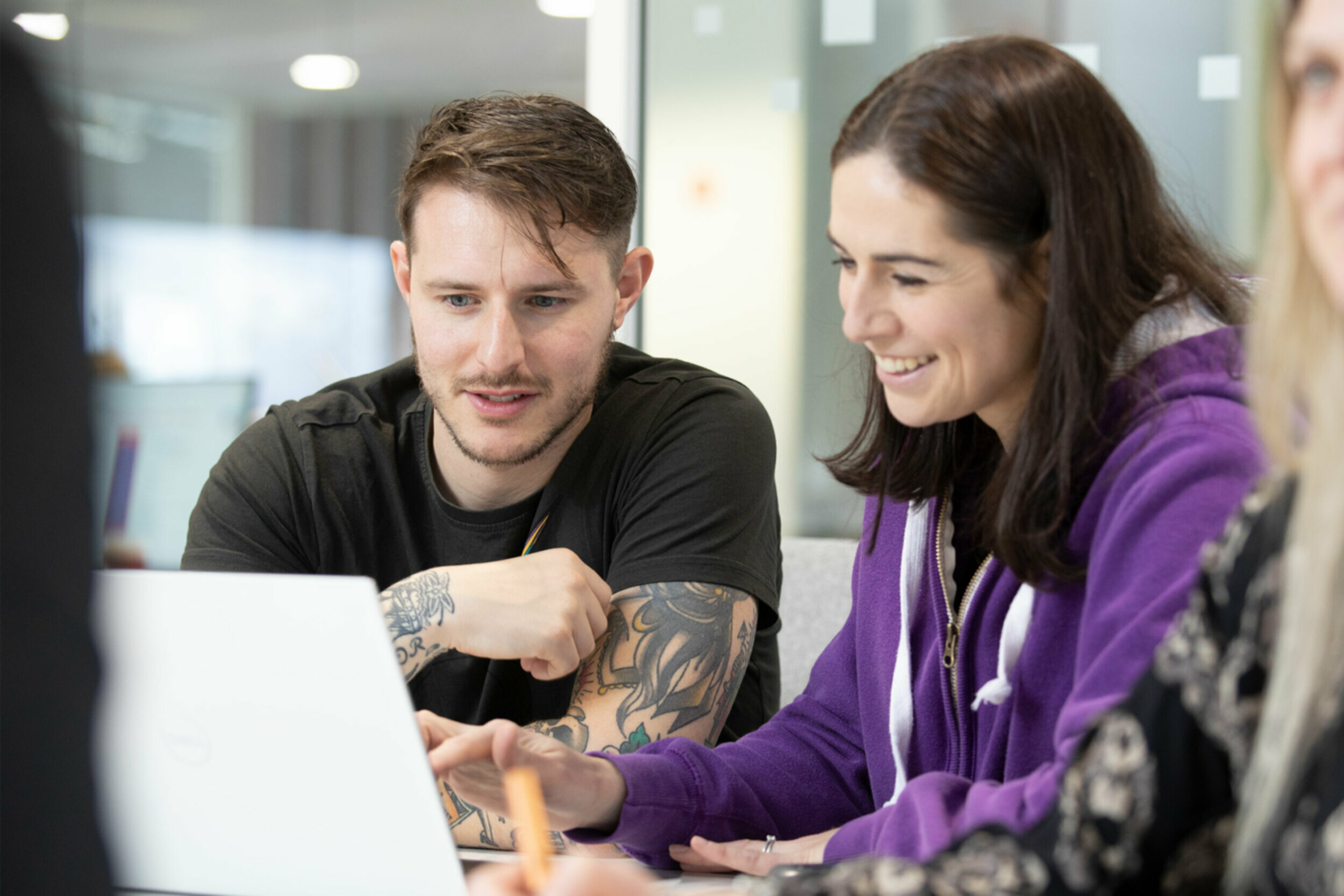 a man and woman are smiling at a laptop