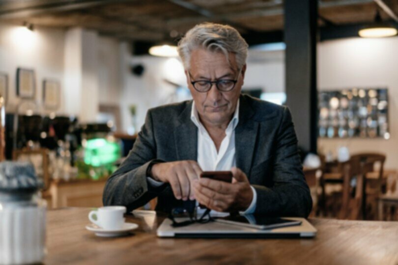 businessman in a coffee shop using app based mobile compliance recording