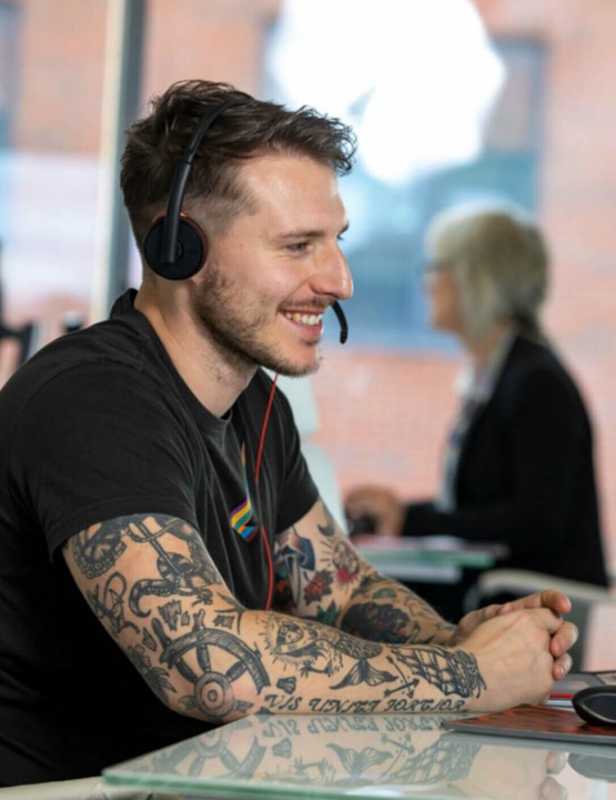 Man sitting at desk with headset on smiling