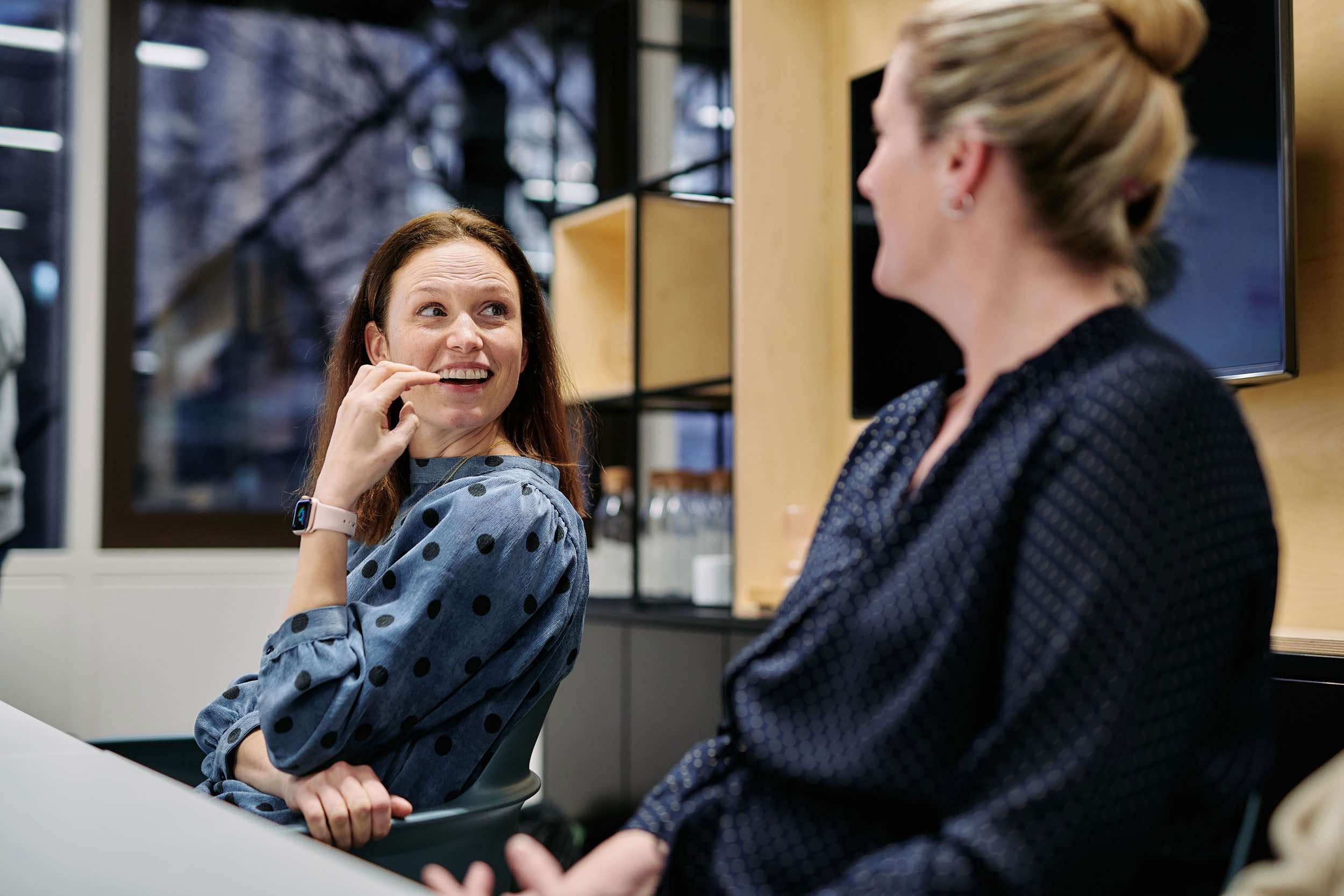 Two women sitting at office desks talking