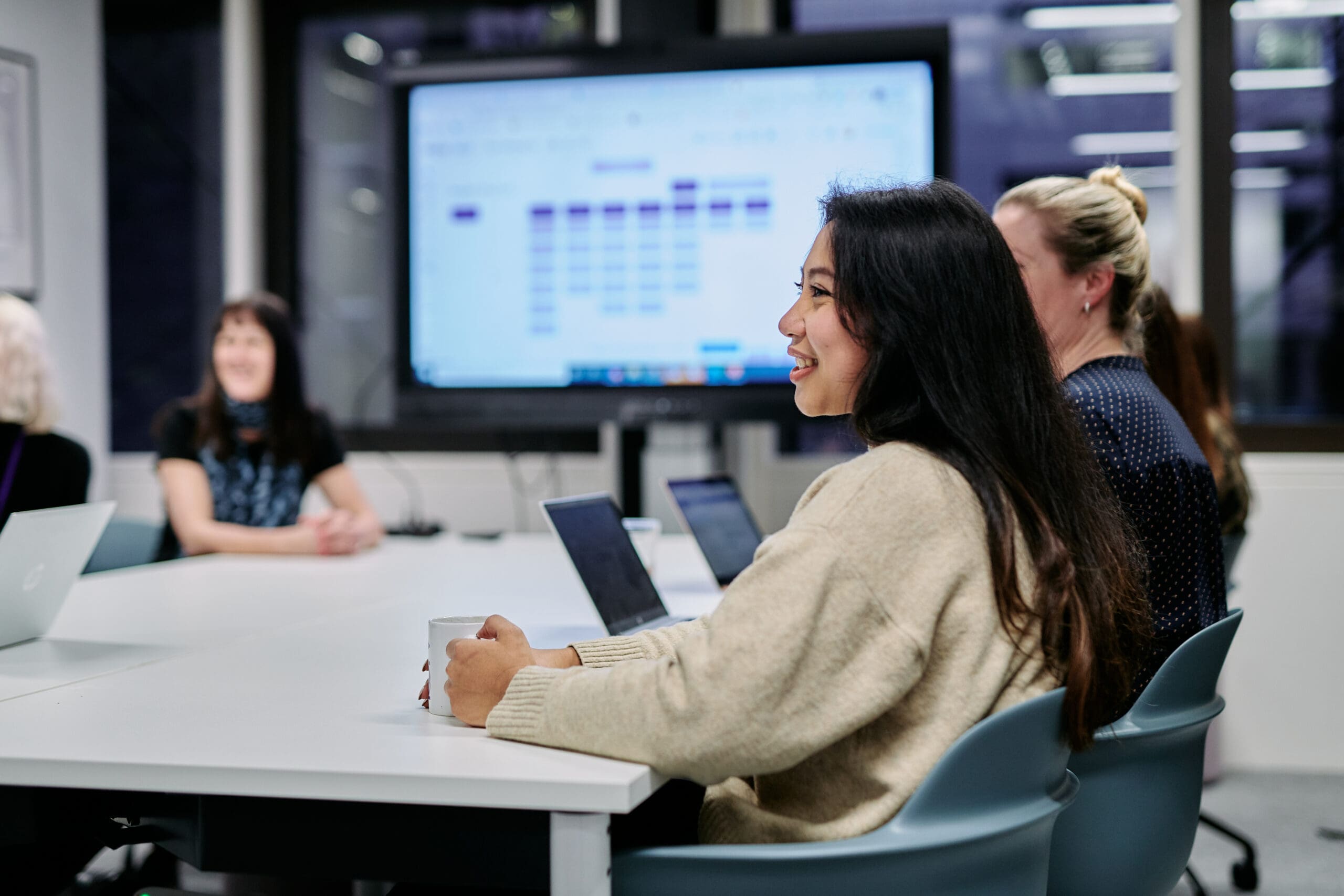 Woman sitting at office desk with others