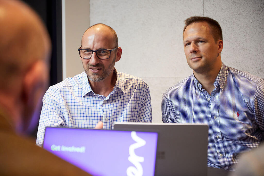 Two men sitting in front of a laptop