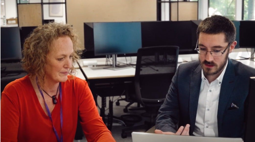 A man and woman sitting at office computer desk working