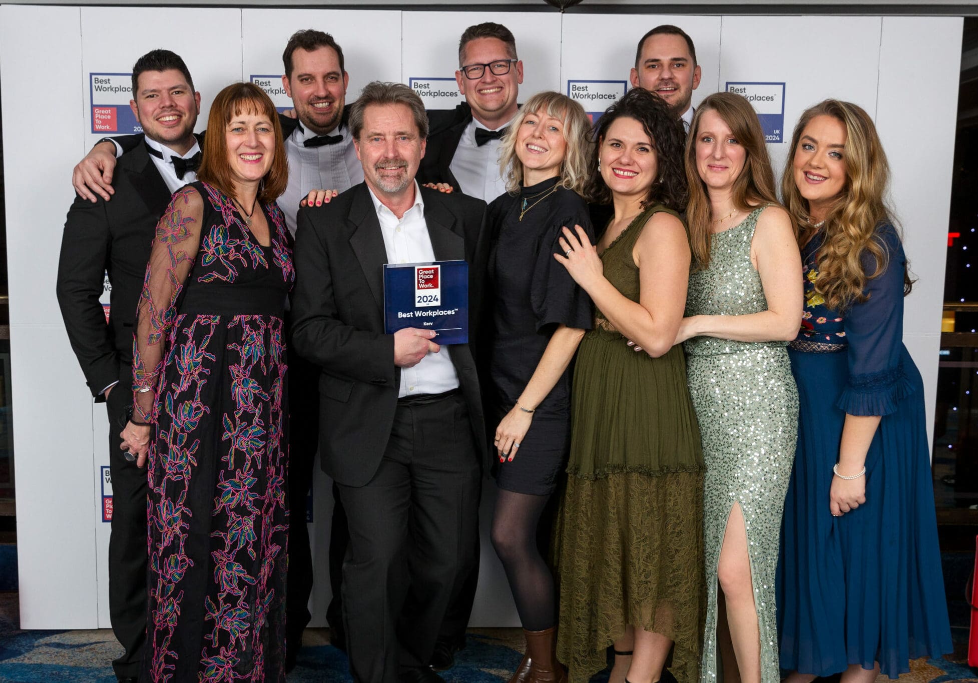 Group of people smiling and posing with Great Place to Work plaque