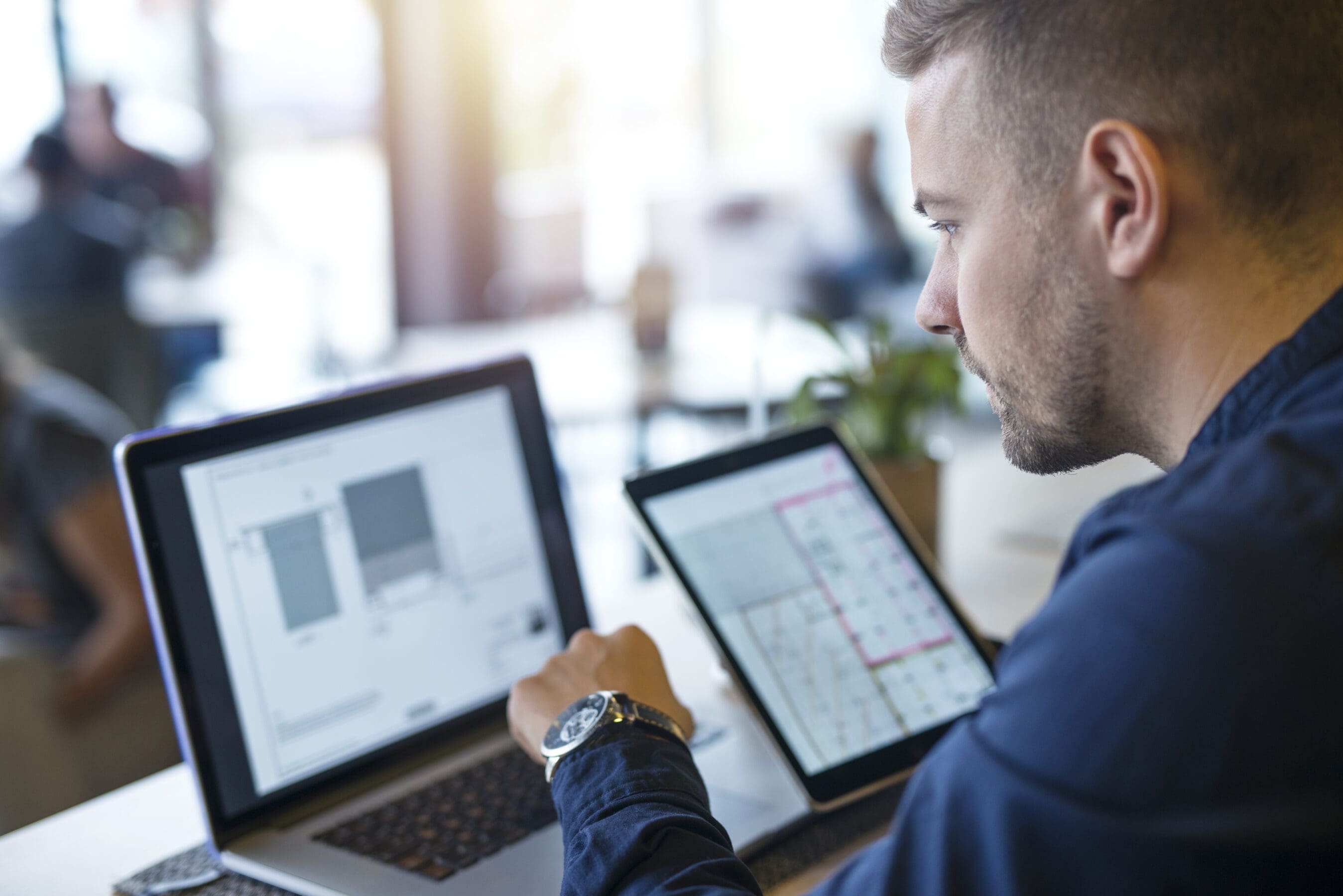 Business man looking and analyzing projects on his laptop computer and tablet.