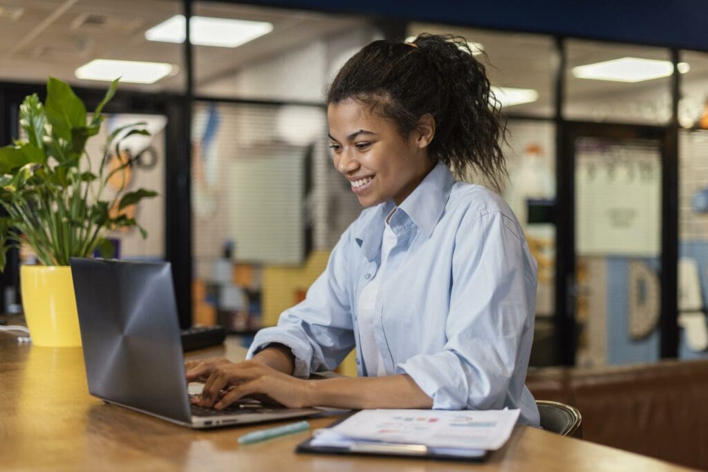 Woman smiling while typing on laptop